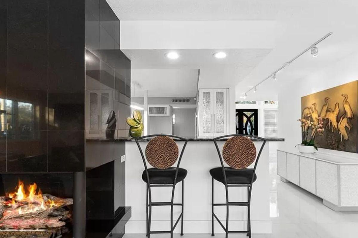 Notice the Bold Black Fireplace in This Sleek Kitchen Bar Area