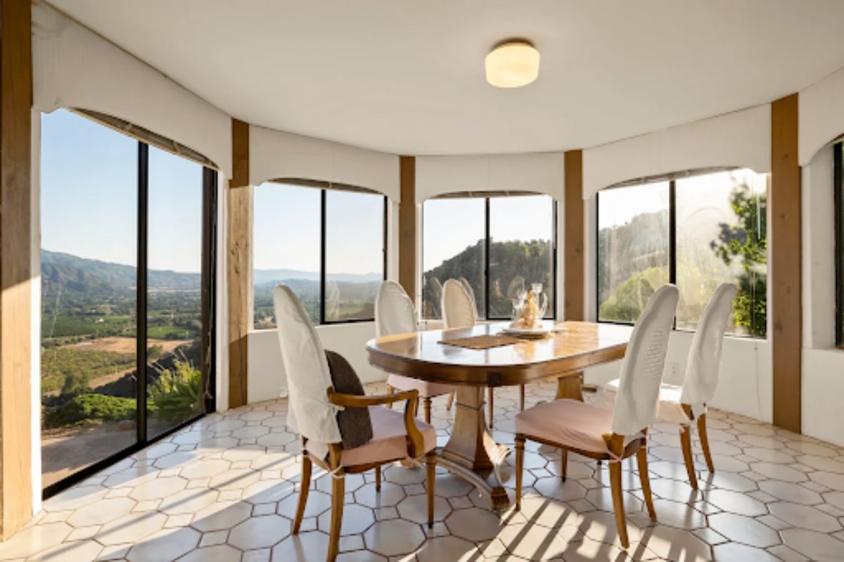 The dining area is surrounded by large windows that allow natural light to enter the room.
