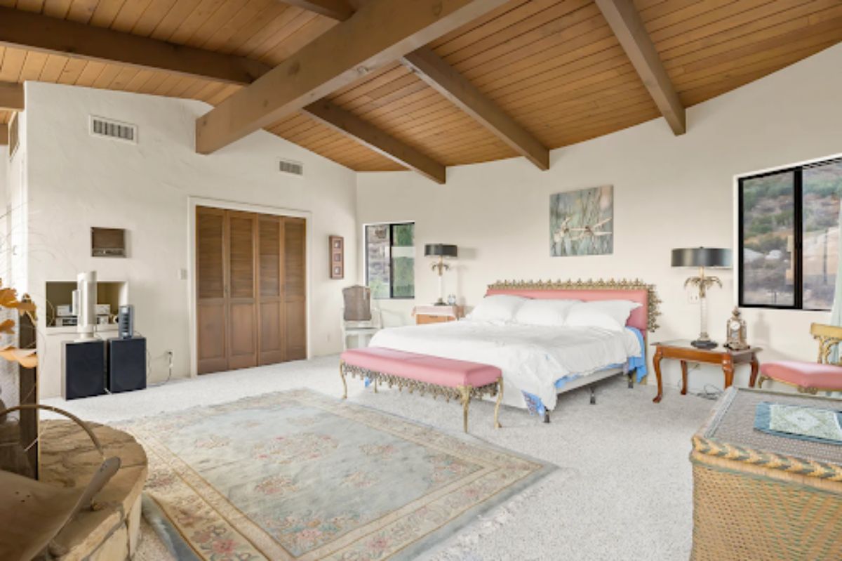 The primary bedroom includes the same beamed and wood ceiling.
