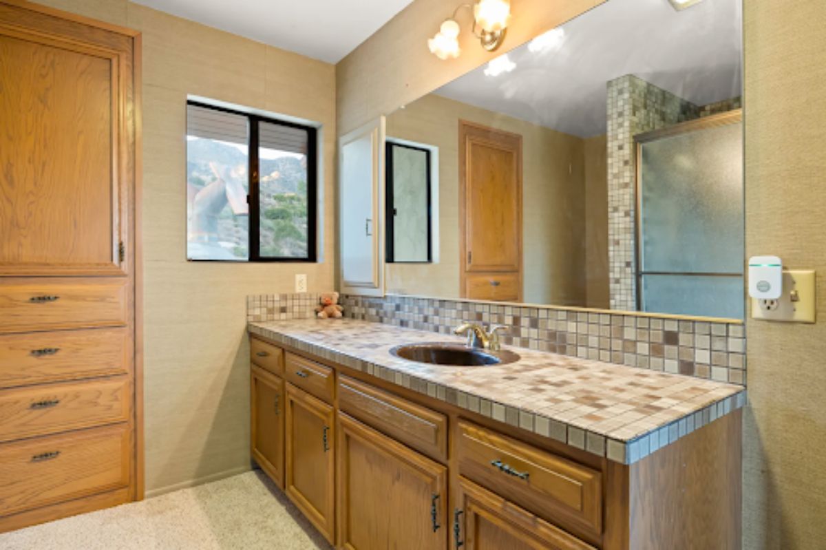 The en-suite bathroom features a large vanity mirror and sink.