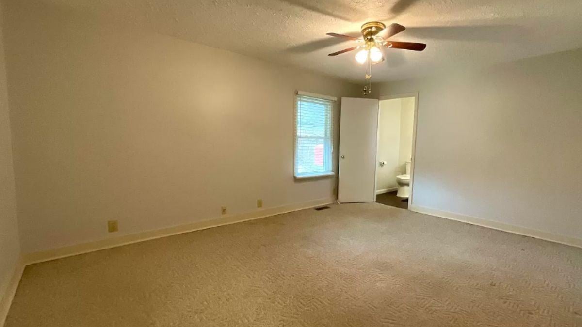 Simple Bedroom With a Functional Ceiling Fan and Direct Bathroom Access