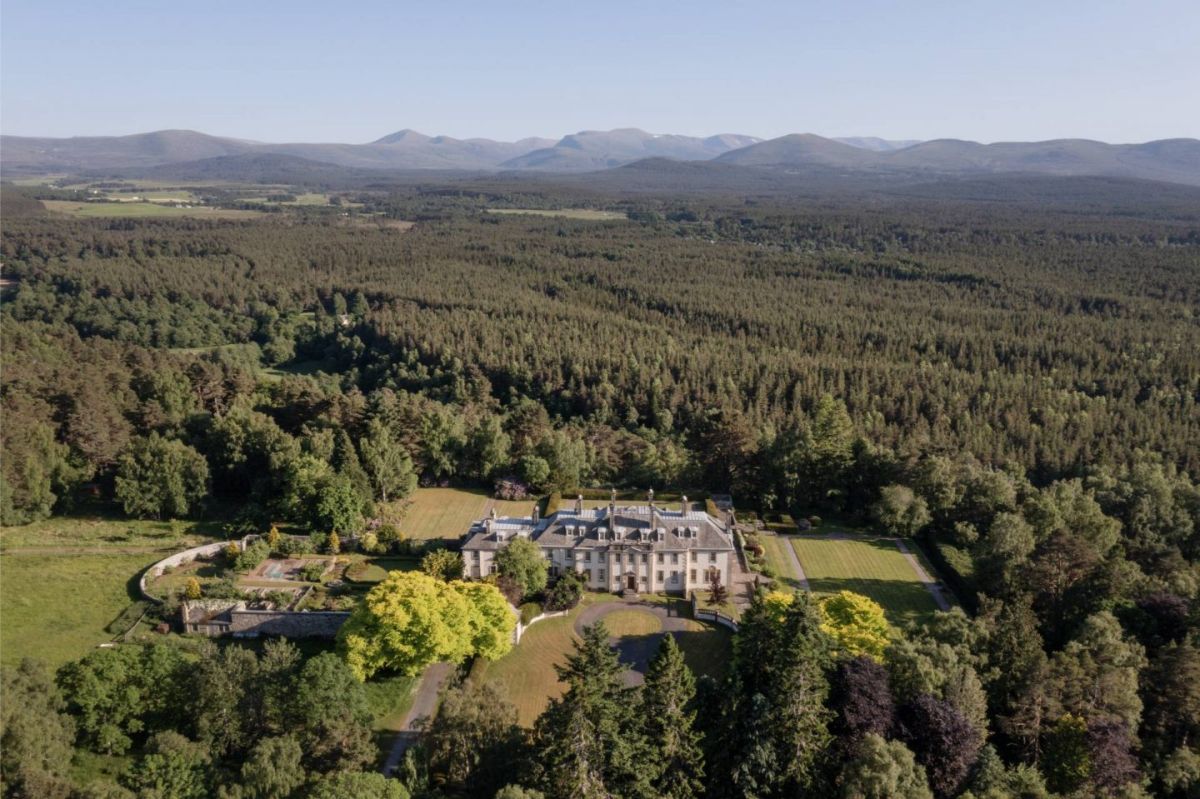Large stone manor is set deep within wooded land.