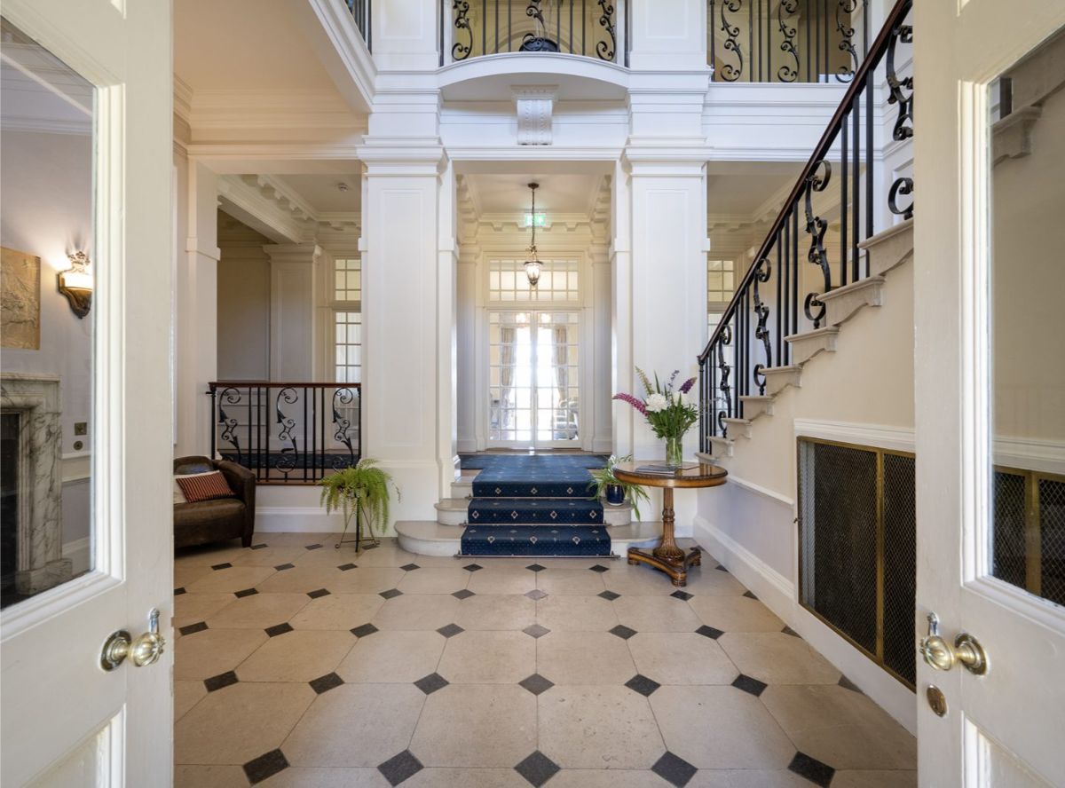 Double doors open to a tall foyer with black-trimmed staircases on each side.