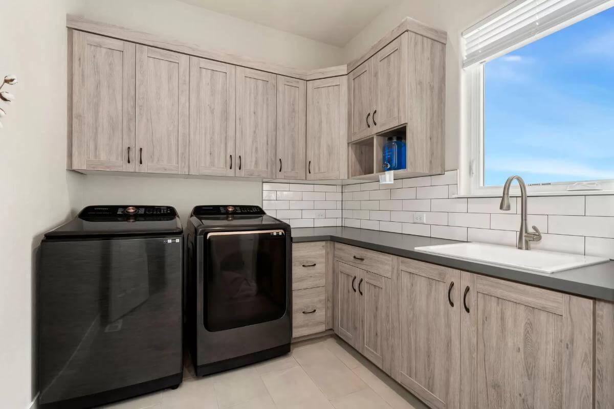 Functional Laundry Room with Sleek Black Appliances and Natural Cabinets
