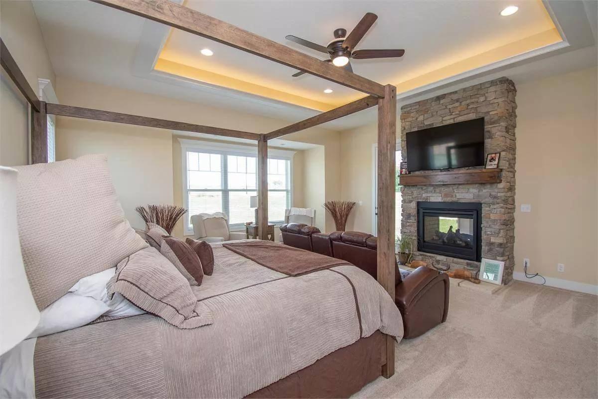 Experience Relaxation by the Stone Fireplace in This Master Bedroom