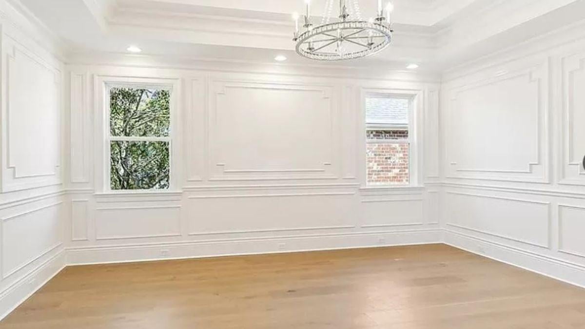 Check Out the Intricate Wainscoting and Modern Chandelier in This Bright Room