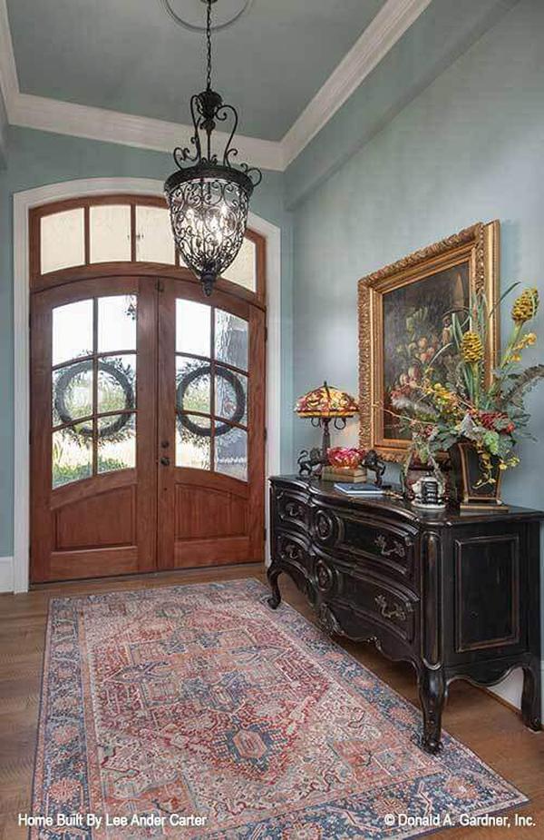 Elegant Entryway with Intricate Chandelier and Curved Wood Doors