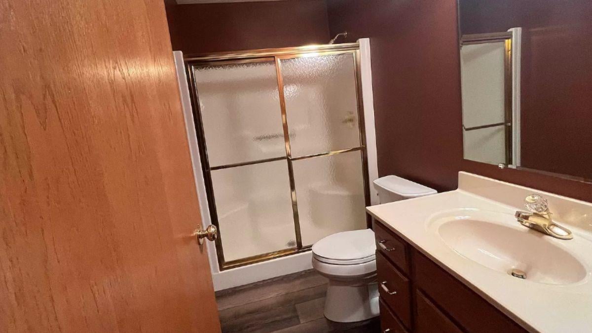 Compact Bathroom with Rich Wood Tones and Elegant Shower Doors