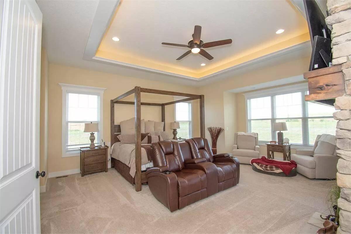 Spacious Master with a Cozy Seating Nook and Walnut Canopy Bed
