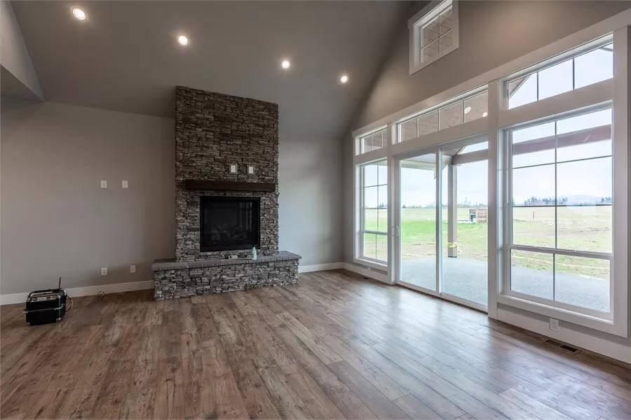 Admire the Floor-to-Ceiling Windows Next to This Stone Fireplace