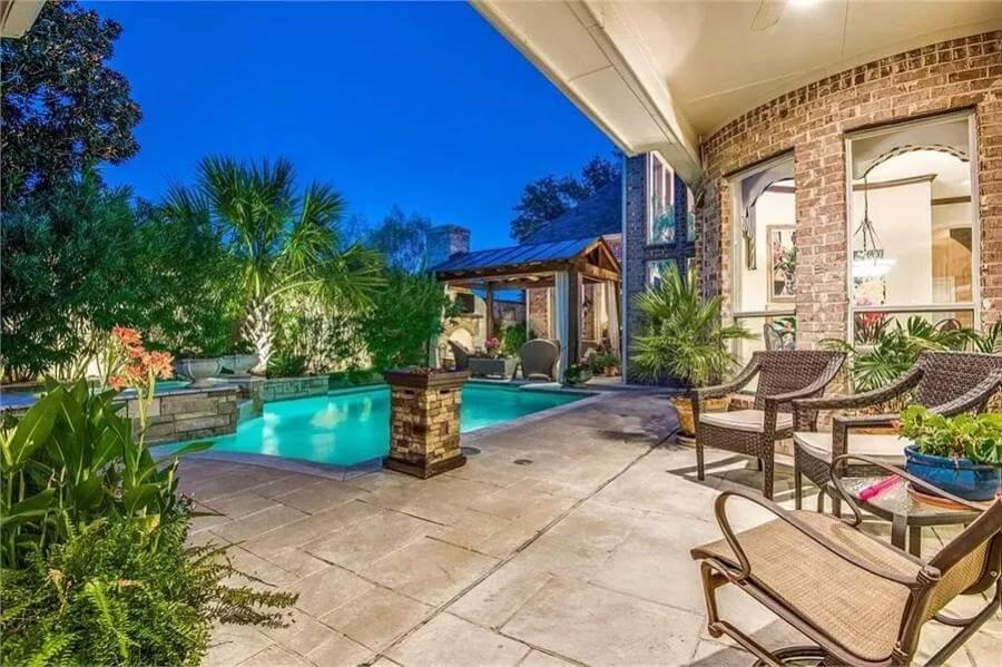 Explore This Inviting Poolside Retreat with Lush Greenery and a Cozy Pergola