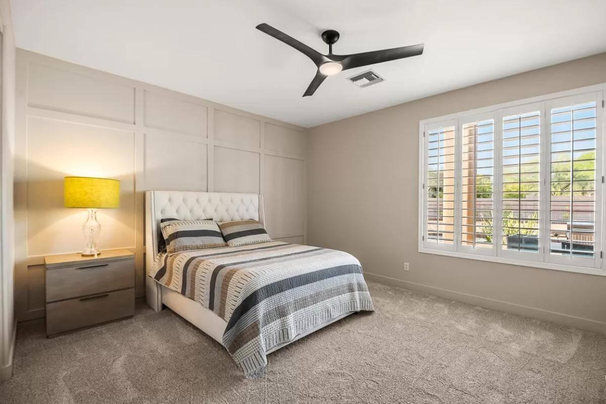 Minimalist Bedroom with Striking Ceiling Fan and Paneled Accent Wall