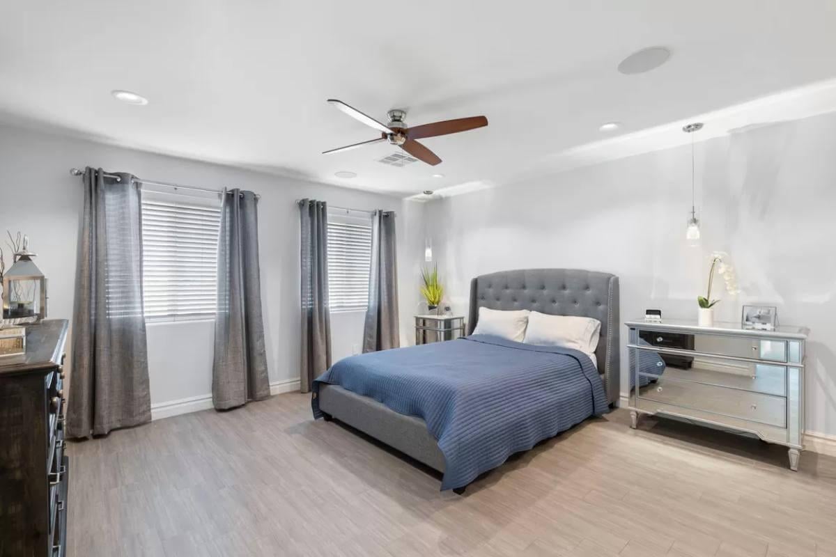 Sleek Bedroom with Mirrored Accents and a Stylish Ceiling Fan