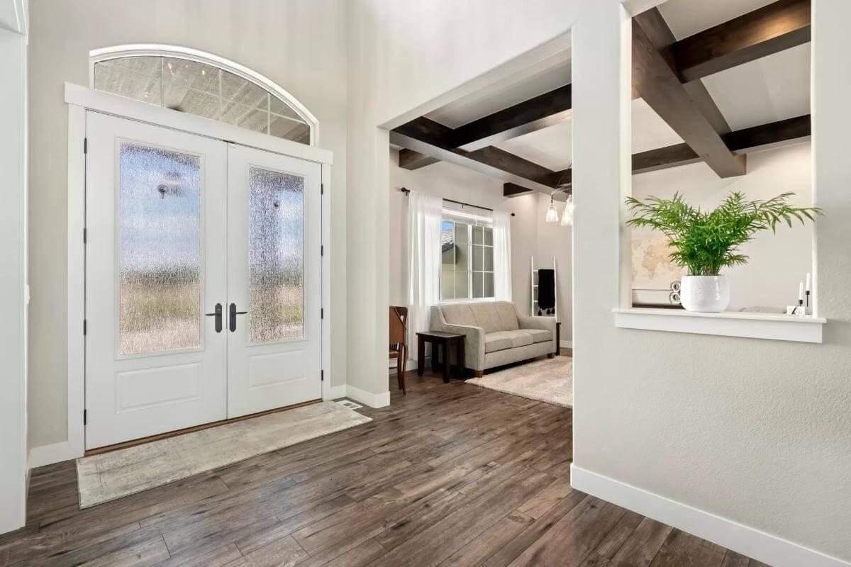 Welcoming Entryway with Textured Glass Doors and Beamed Living Space