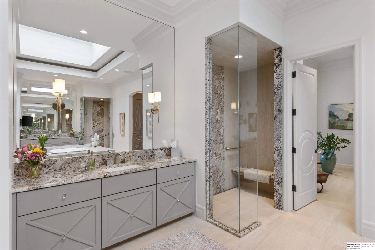Bathroom with granite-topped vanity, glass-enclosed shower, and marble wall accents.