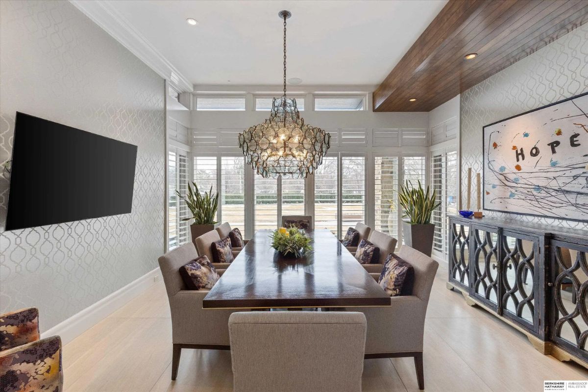 Dining room with rectangular table, crystal chandelier, accent wall, and sideboard under artwork.