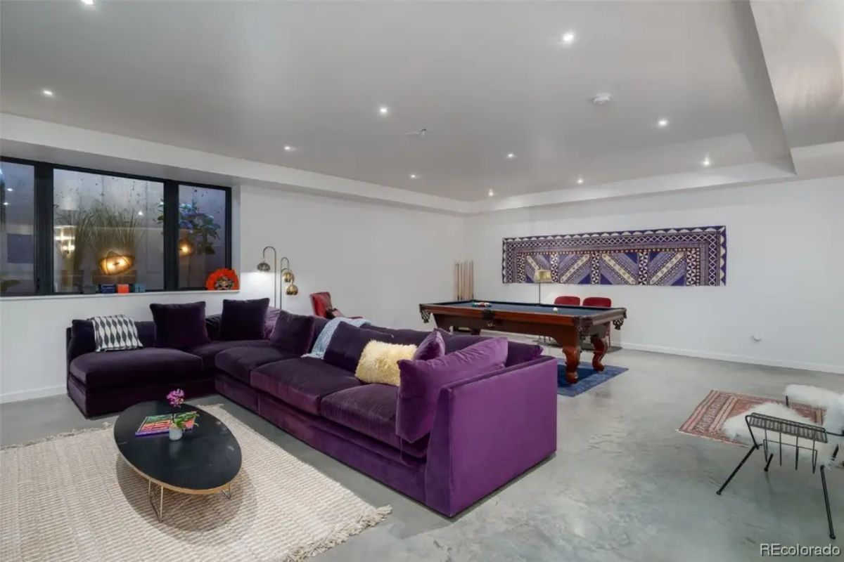 Entertainment room with purple sectional sofa, pool table, and recessed ceiling lights.