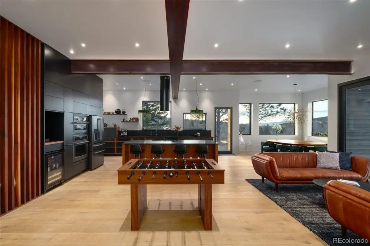 Open-concept space with foosball table, wood-accented kitchen, leather seating, and dining area.