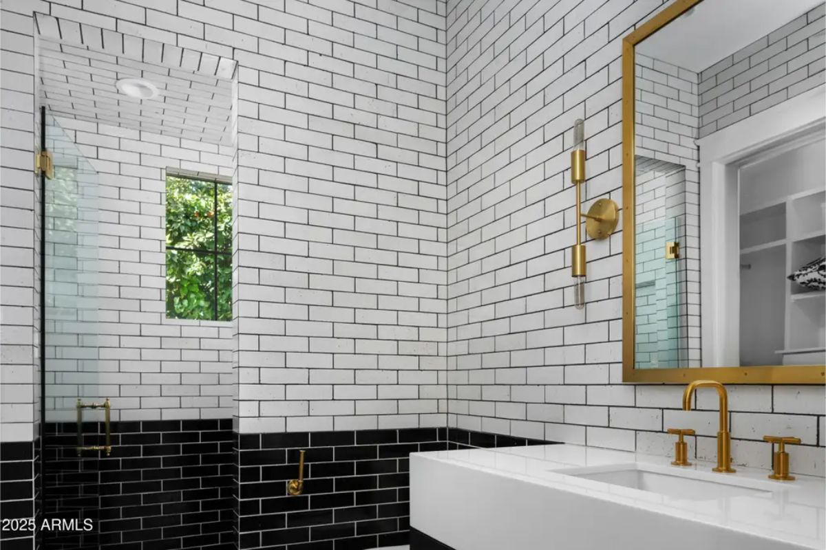 Bathroom with subway tile walls, gold fixtures, and large mirror.