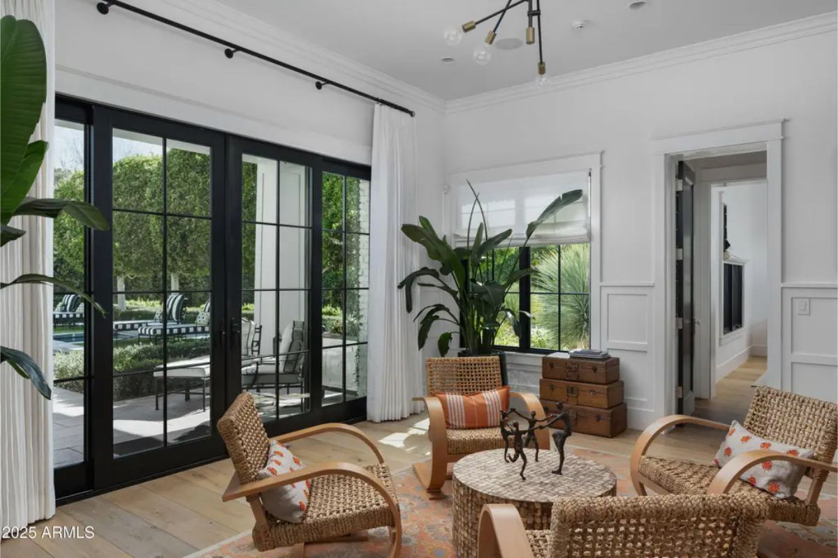 Sunroom with wicker chairs, round table, and double doors leading outside.
