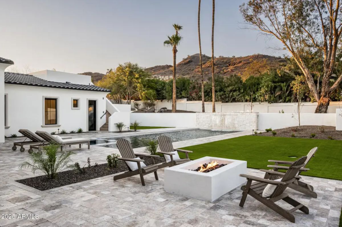 Backyard layout shows paver patio with fire pit surrounded by Adirondack chairs next to pool and artificial turf lawn.