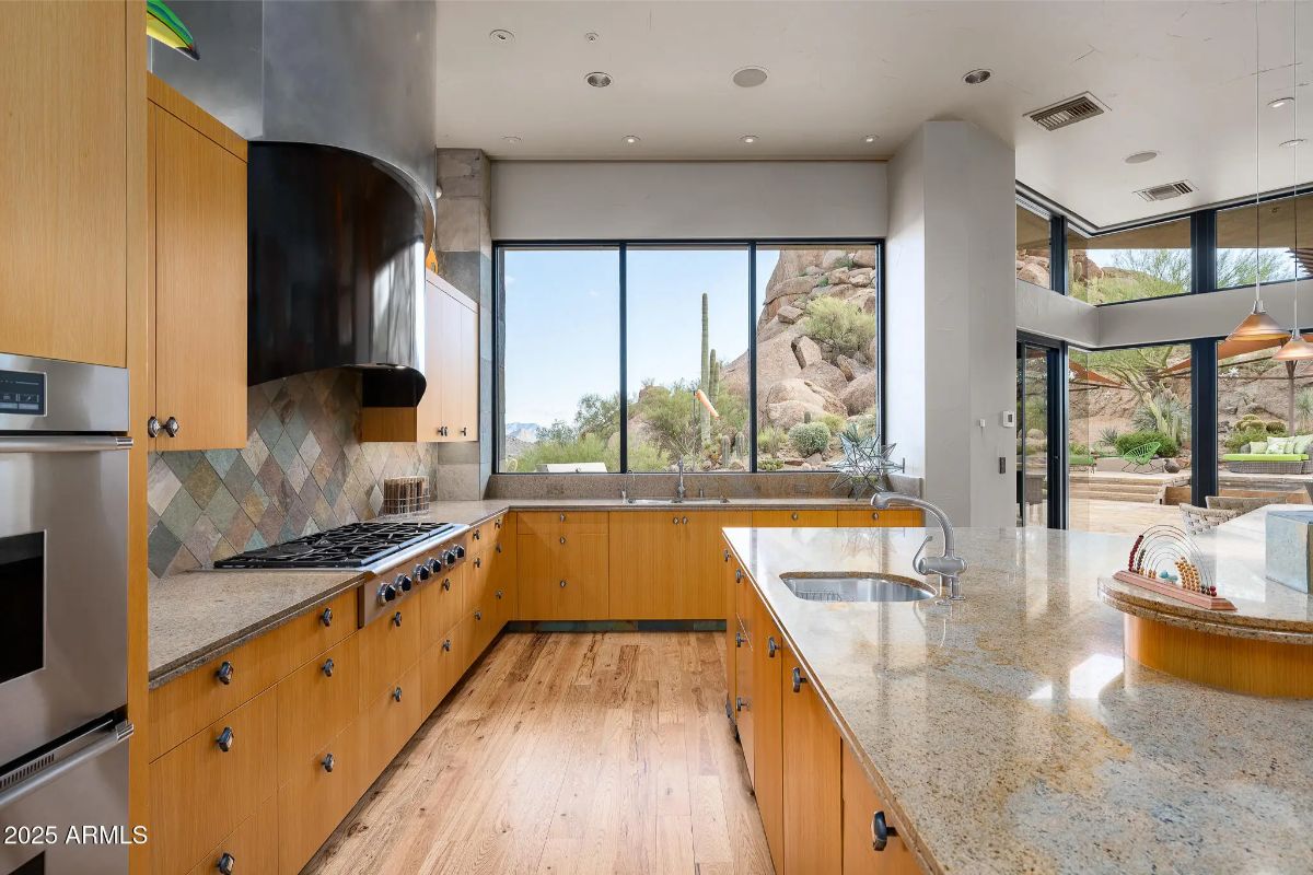 U-shaped kitchen layout with granite countertops and large windows offering mountain views.