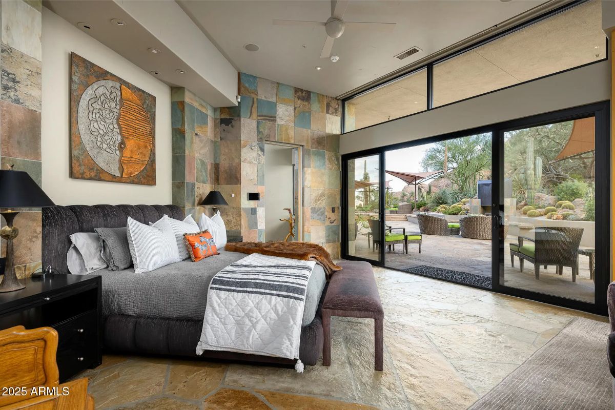 Bedroom with patterned stone wall, sliding glass doors, and access to an outdoor patio.