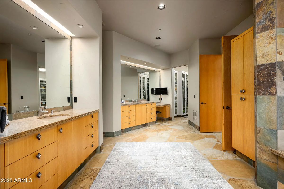 Bathroom with dual vanities, light wood cabinetry, and large mirrors.