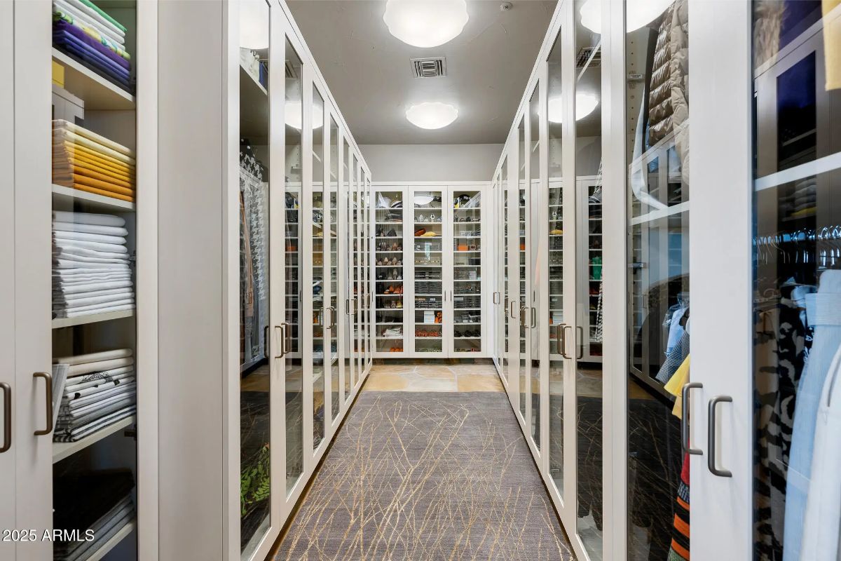 Walk-in closet with glass-front cabinetry and ceiling lights.