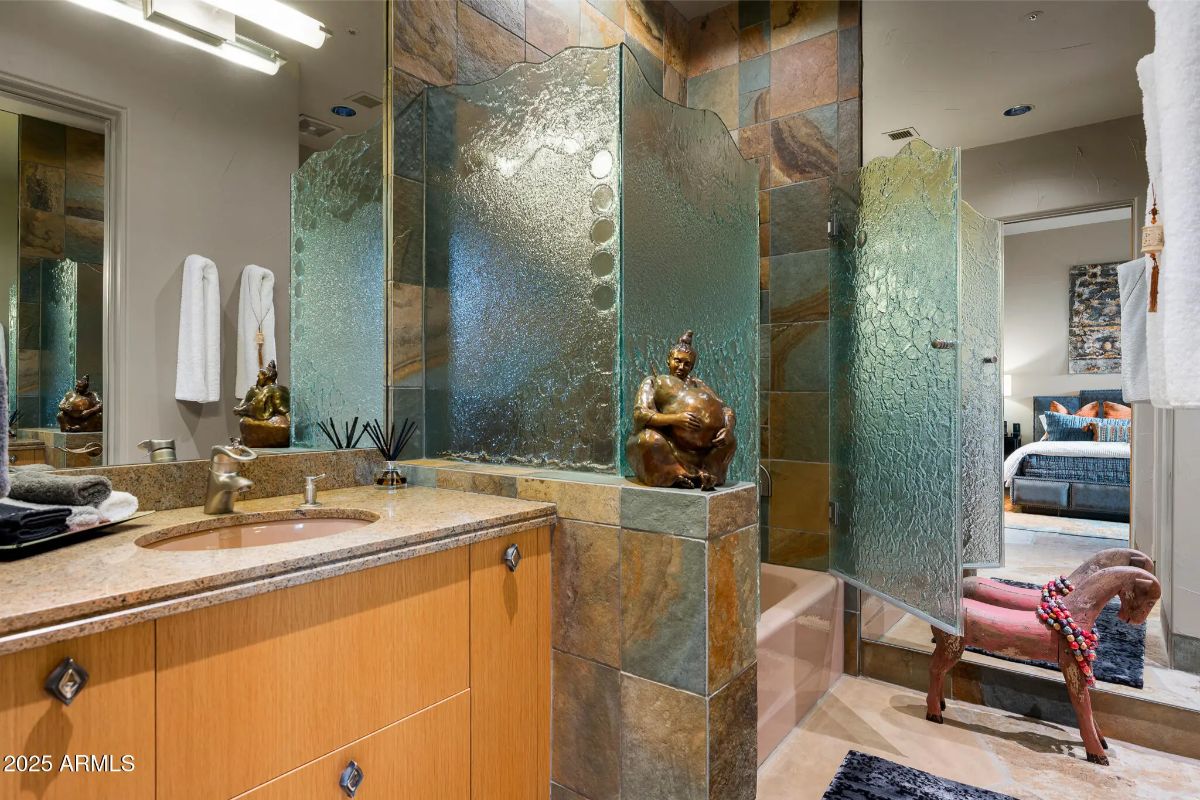 Bathroom with frosted glass shower enclosure, stone tile walls, and bronze fixtures.