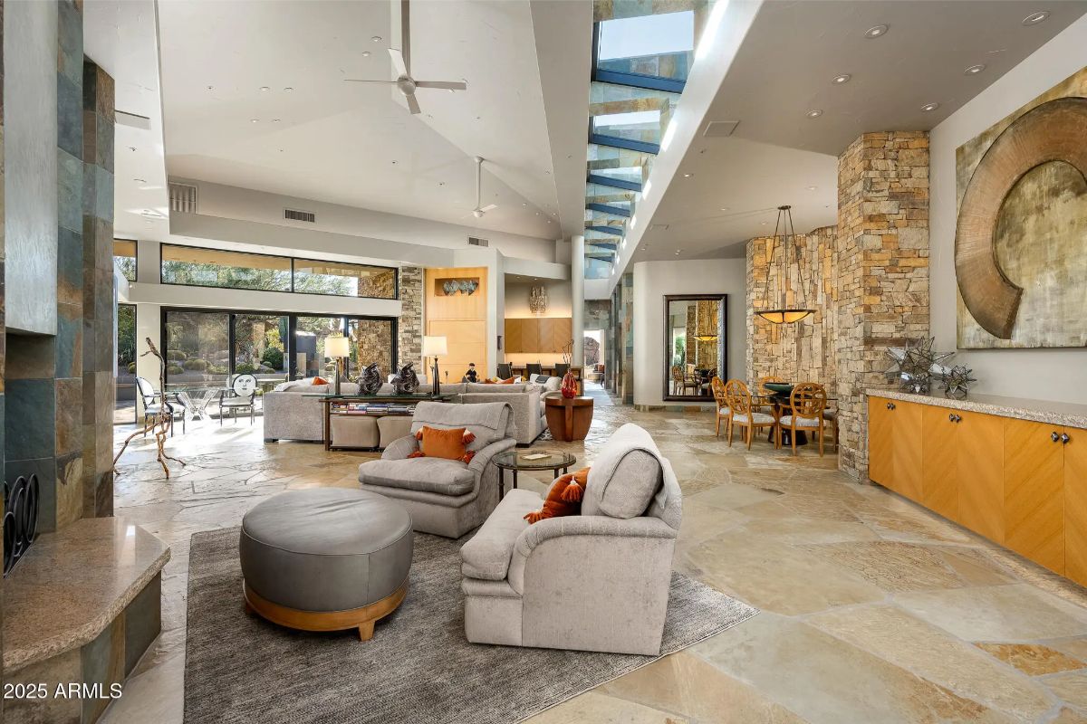 Open-concept interior with skylights, stone fireplace, dining area, and built-in cabinetry.