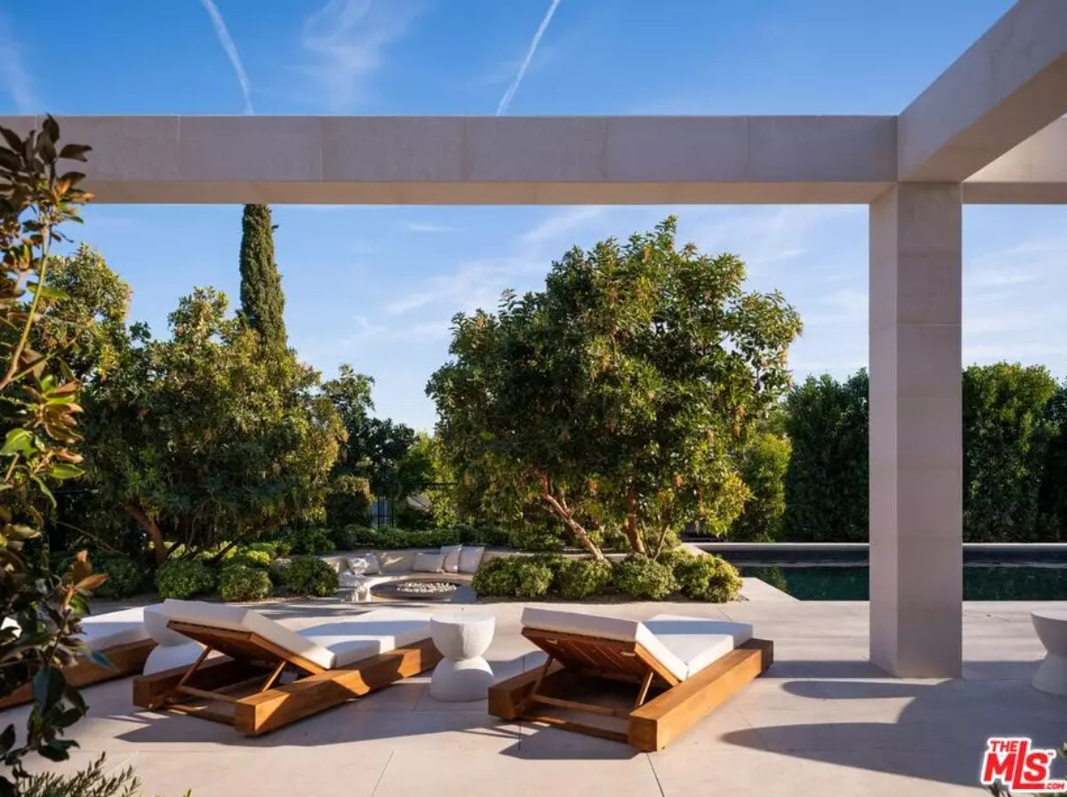 Poolside terrace with paired wood-framed loungers shaded by large structural beams.