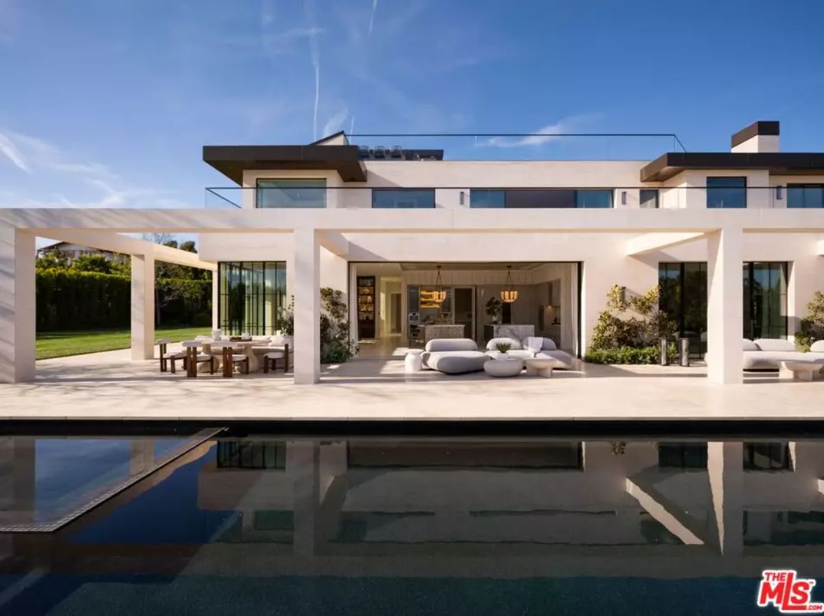 Full rear facade with tall glass doors, lounge furniture, dining area, and pool reflecting structure.
