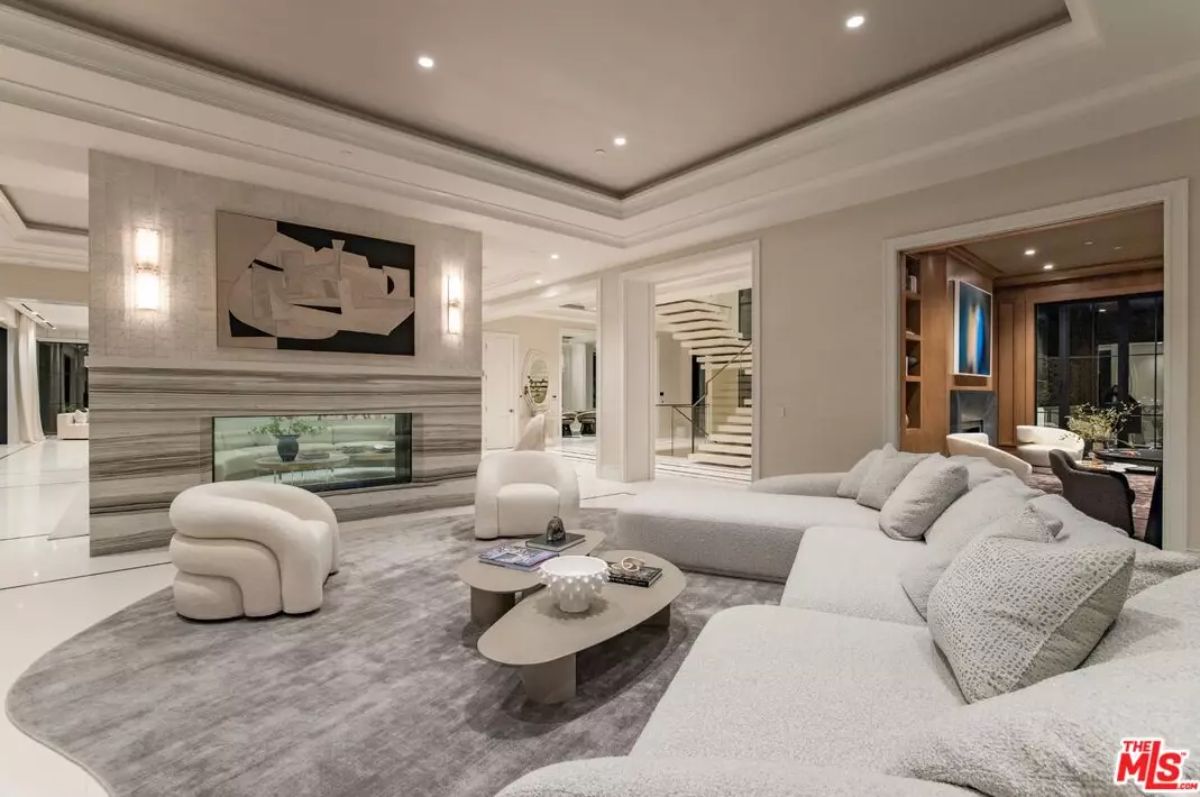 Sitting area with sectional and accent chair centered around double-sided fireplace and abstract art.