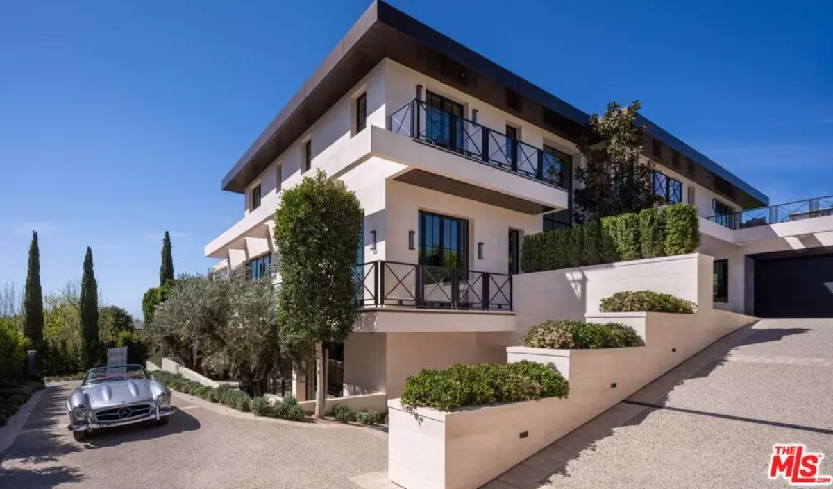 Multi-level residence with tiered landscaping, balconies, and curved driveway with parked car.