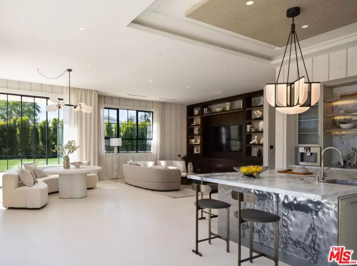 Open-concept kitchen and family room with marble island, TV wall, round table, and curved sofa.