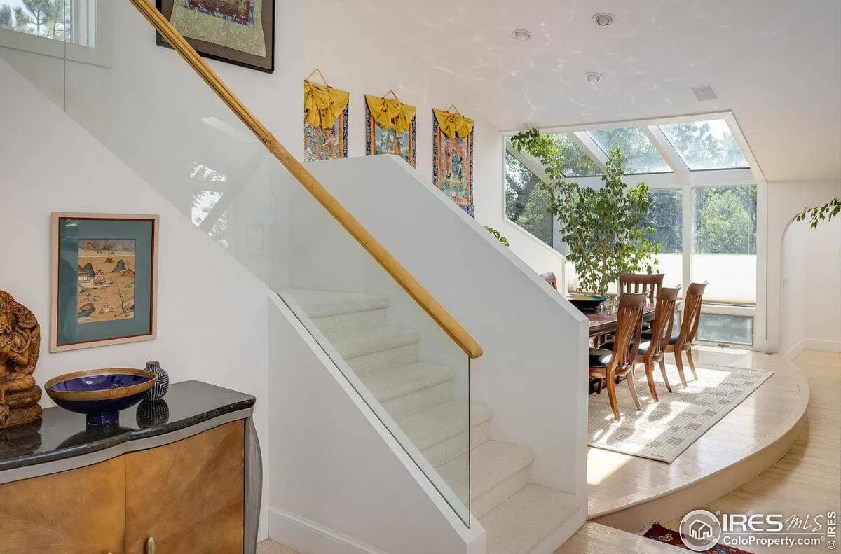 Admire the Glass Staircase Leading to a Sunlit Dining Area