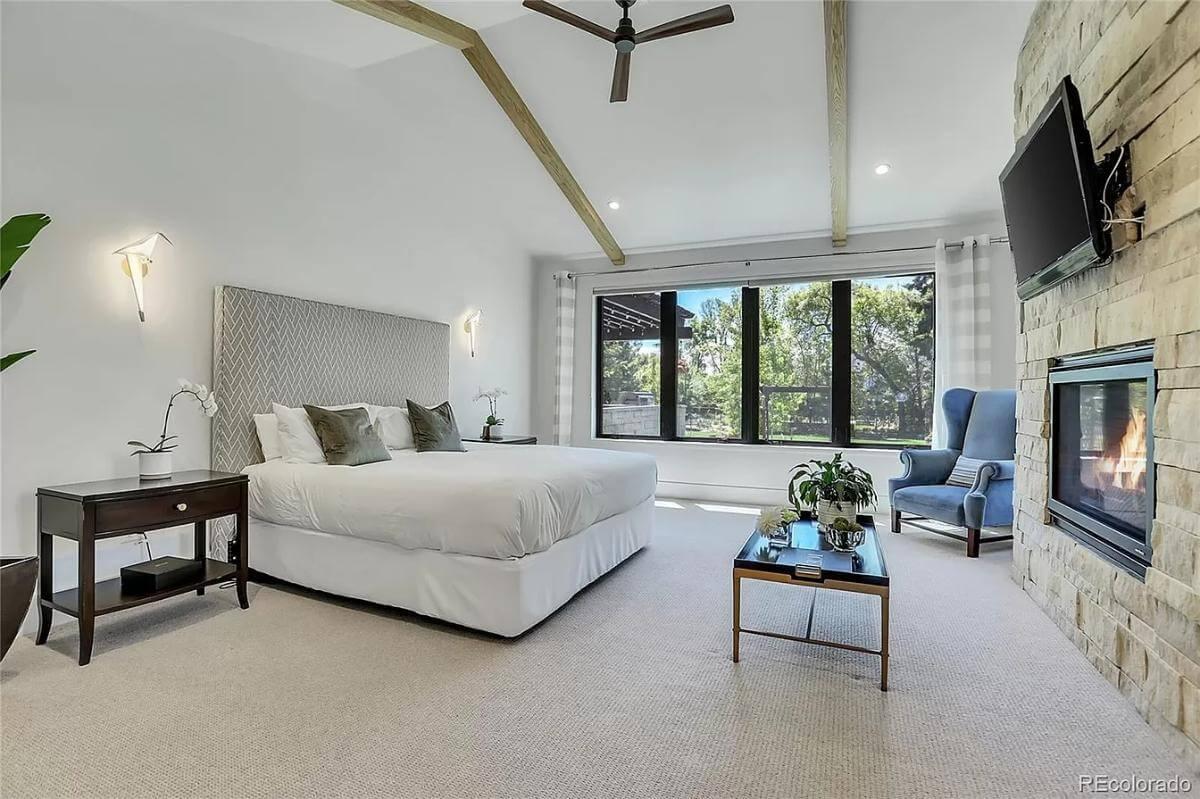 Notice the Soaring Ceilings and Textured Stone Fireplace in This Serene Bedroom