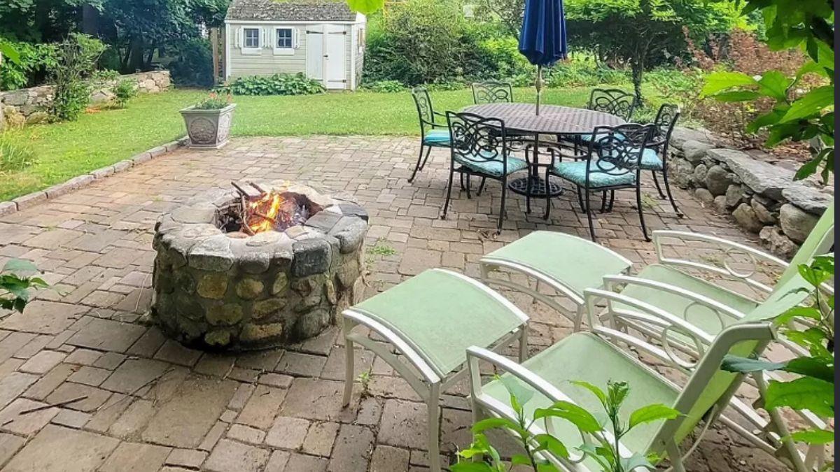Charming Backyard Patio with Stone Fire Pit and Lush Surroundings