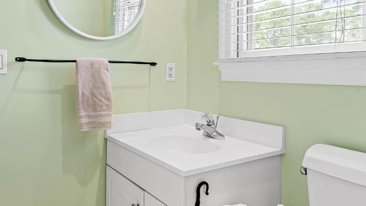 Simple Powder Room with Pastel Walls and Round Mirror