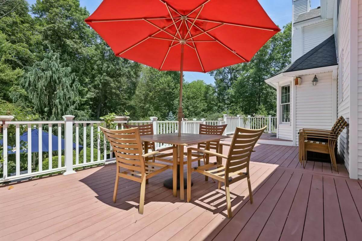 Enjoy the Deck with a Bold Red Umbrella and Wooden Seating Arrangement