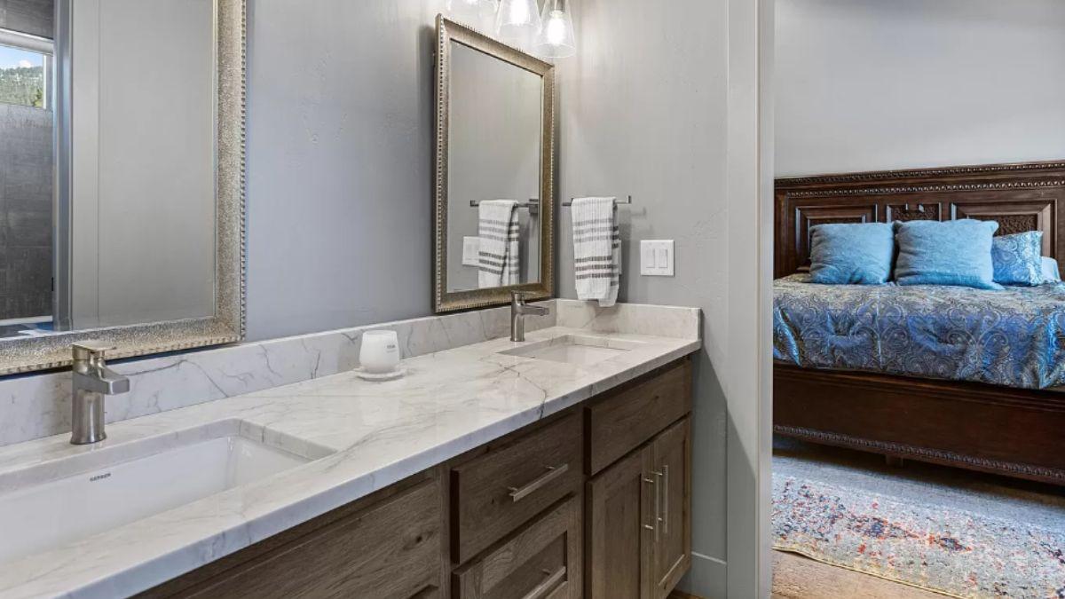 Dual Vanity Elegance with a Peek into a Plush Bedroom