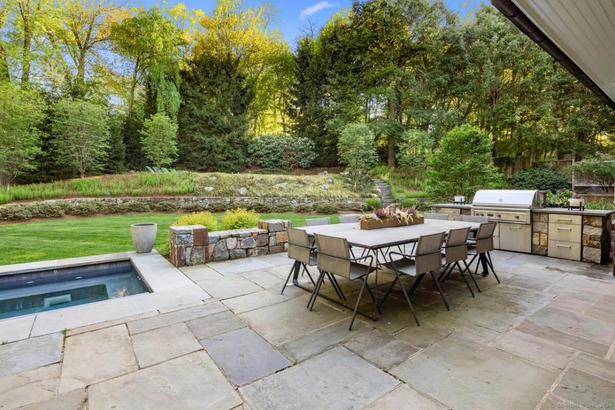 Outdoor Dining Oasis with Built-In Grill and Lush Backdrop
