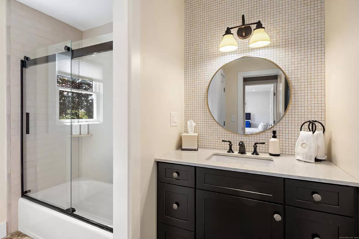 Simple Elegance: Black Vanity and Round Mirror in This Clean Bathroom Design