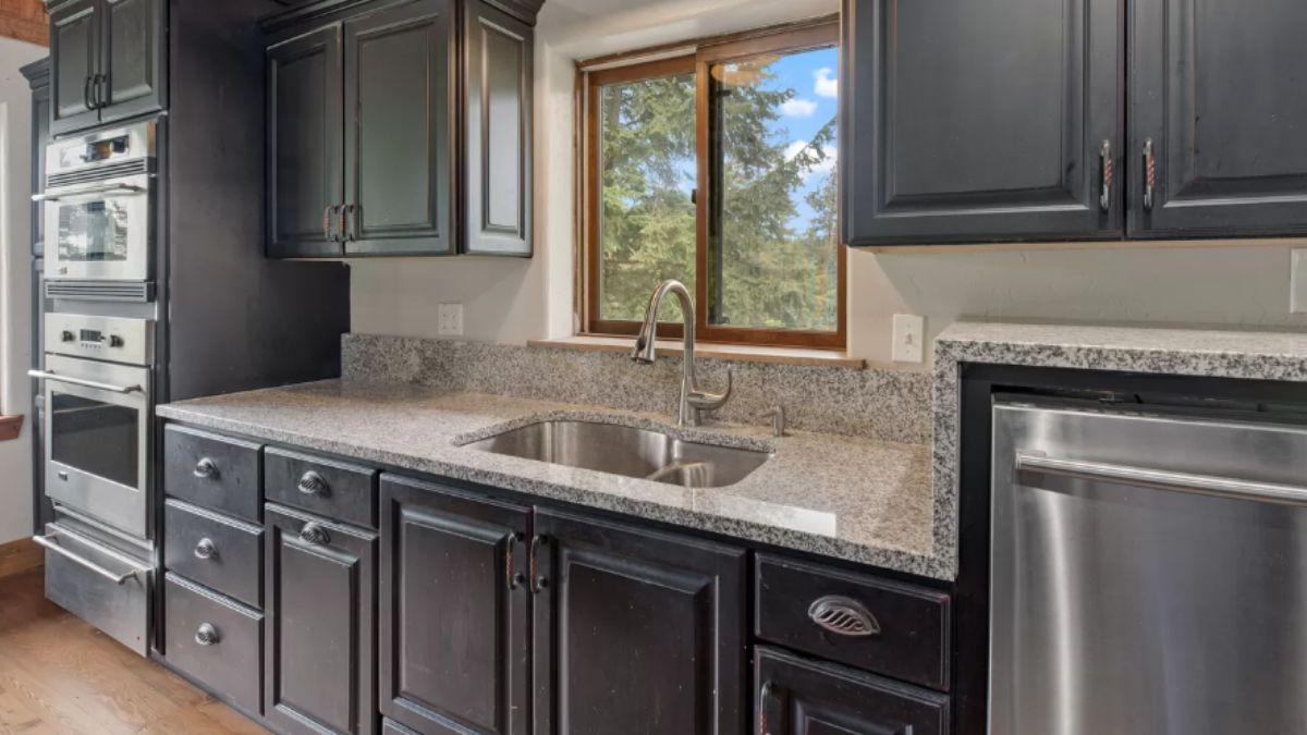 Discover the Blend of Dark Cabinetry and Granite Surfaces in This Kitchen