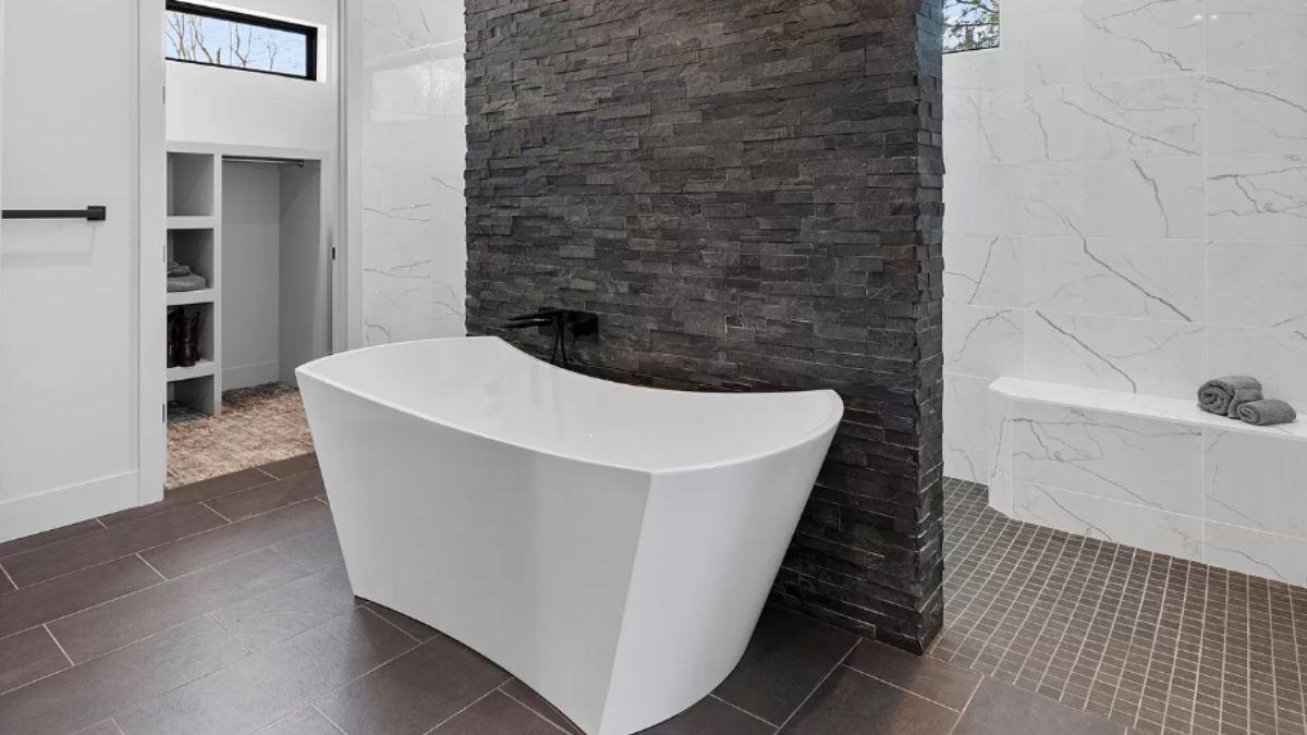 Experience the Tranquility of This Freestanding Tub Against a Textured Stone Wall