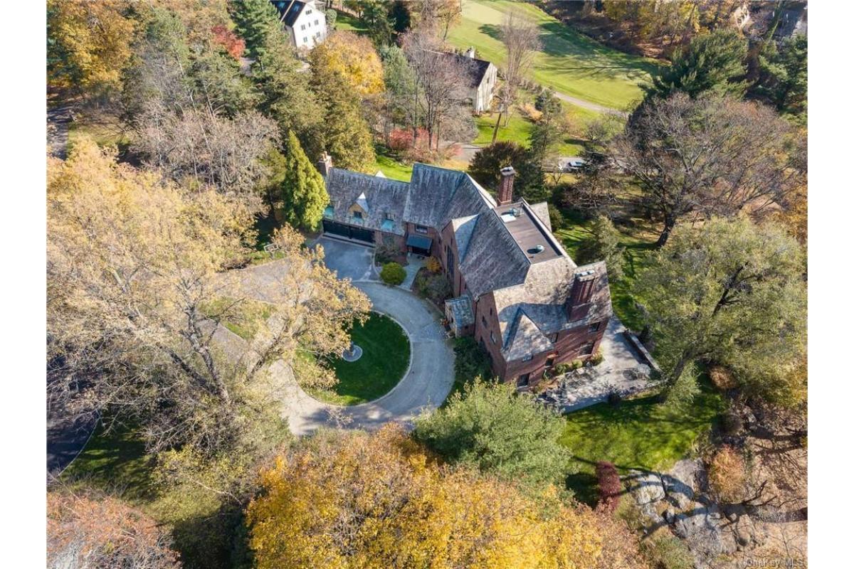 Experience the Grandeur: Aerial View of the Brick Manor Amongst Autumn Foliage