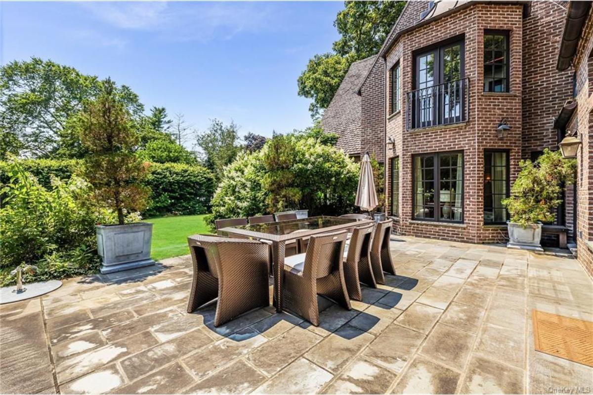Step onto This Patio with Its Brick Backdrop and Elegant Dining Area