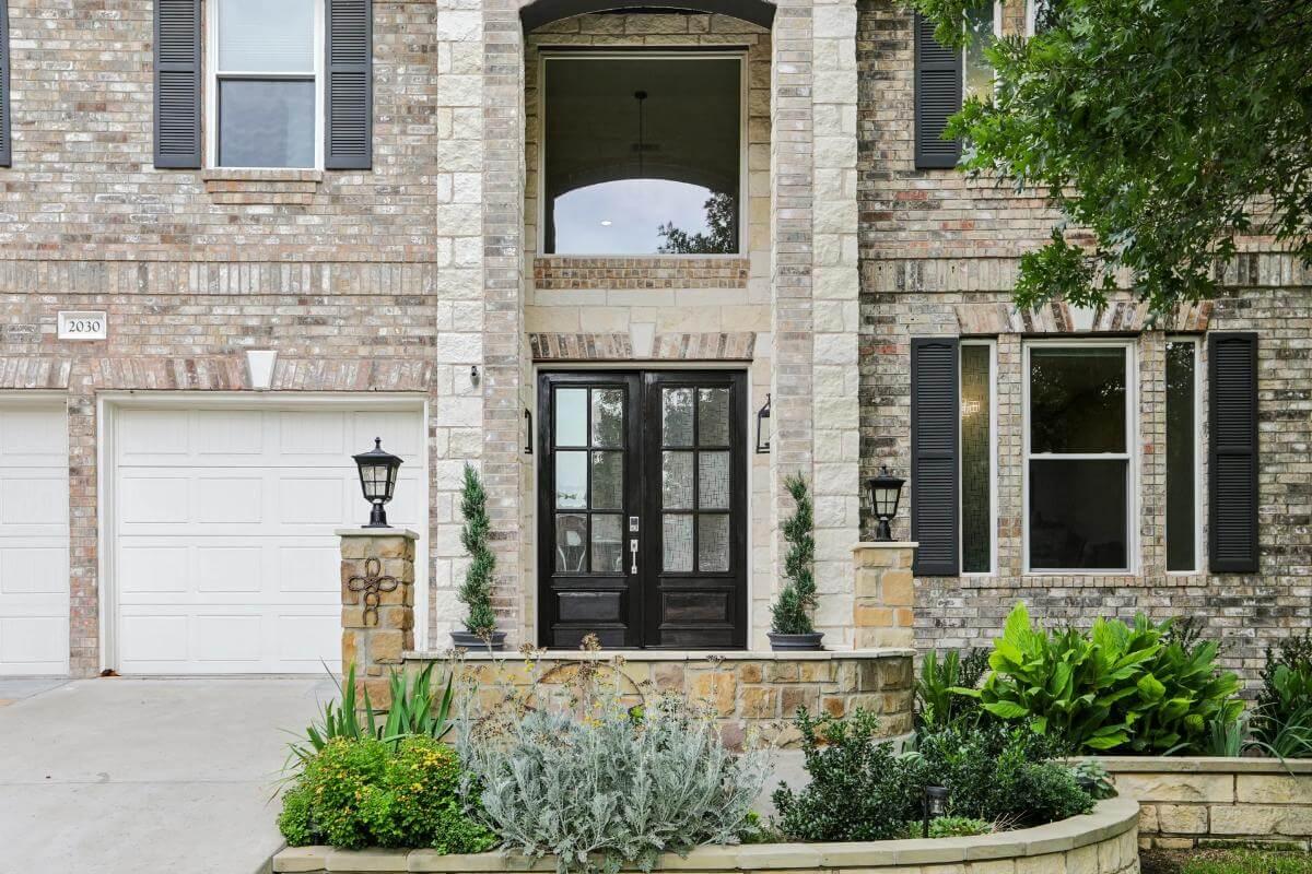 Stately Entrance with Black Double Doors Amidst Textured Brickwork