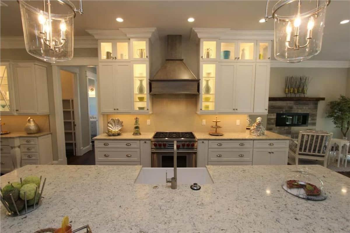A Cozy Kitchen with Illuminated Cabinet Display and Central Island